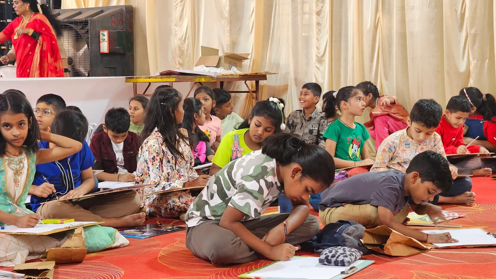 Children drawing on boards together, seated on a red carpet at the February 2026 activity
